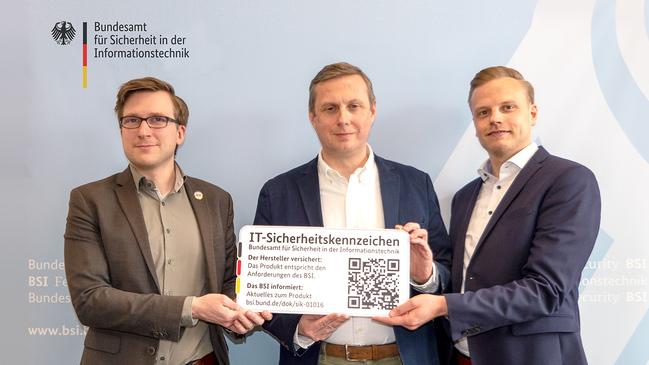 Joshu Wiebe, BSI, übergibt das IT-Sicherheitskennzeichen an Jörg Hammermeister und Alexander Dölling von der EWE Tel GmbH. 
