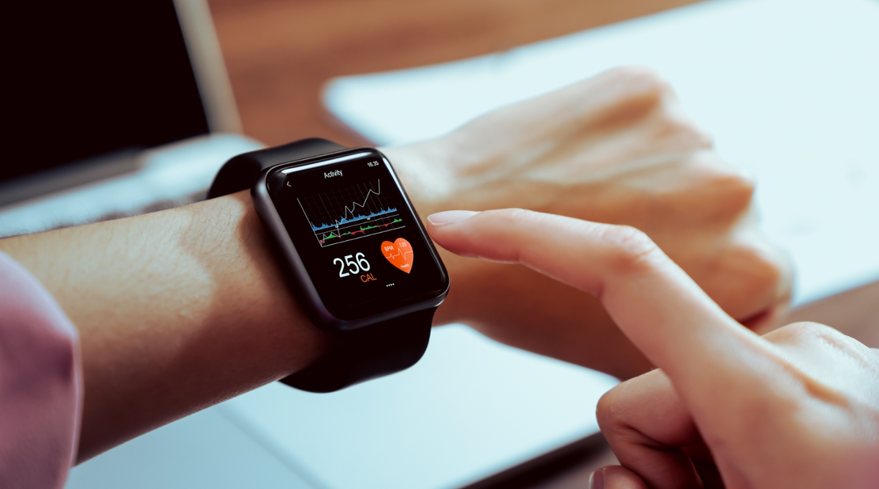 Eine Smartwatch am Handgelenk eines Menschen. Der Bildschirm zeigt ein Herz, eine Zahl und einen Graphen. Eine Hand deutet auf die Anzeige. (Quelle: © sitthiphong / Adobe Stock) Eine Smartwatch am Handgelenk eines Menschen. Der Bildschirm zeigt ein Herz, eine Zahl und einen Graphen. Eine Hand deutet auf die Anzeige.